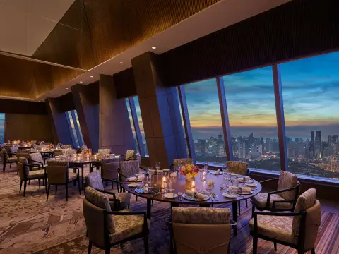 Rooftop dining room with floor-to-ceiling windows over the Manila skyline at dusk, Grand Hyatt