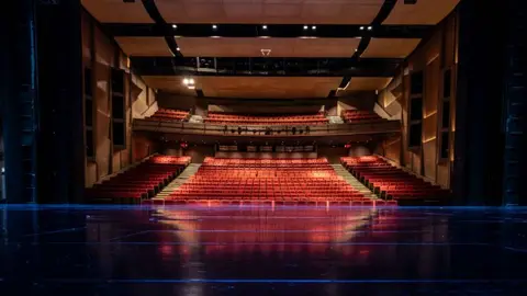View from the stage of the Rockwell Performing Arts Theater auditorium, with red seating and timber wall panels