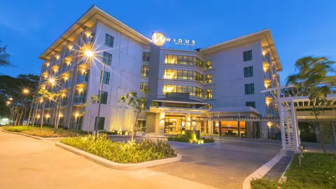 Widus hotel tower and porte-cochère lit at dusk in Clark, Pampanga